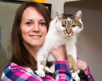 Dark-haired lady holding white and tabby cat
