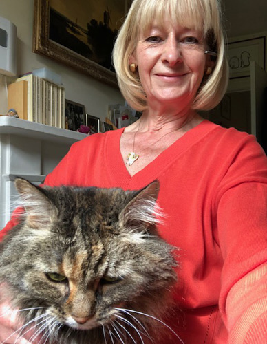 woman with short blonde hair wearing red jumper with brown tabby cat on her lap
