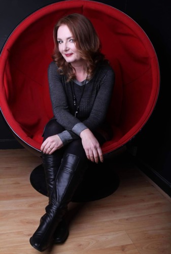 Brunette woman wearing black clothing sitting in red egg chair