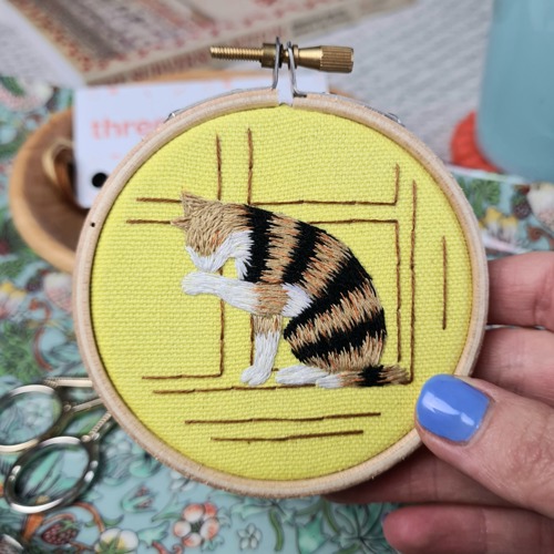 needle painted embroidery of brown-and-black striped cat on yellow background