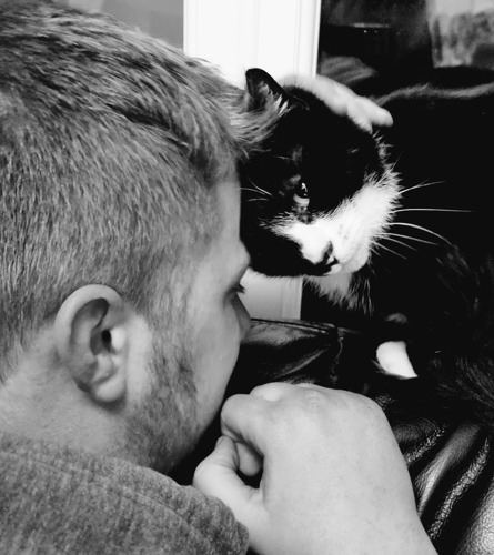 black-and-white photos of a man with short hair and beard head bumping black-and-white cat