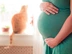 Pregnant woman with ginger cat in background