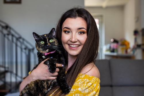 woman with long brown hair holding tortoiseshell cat