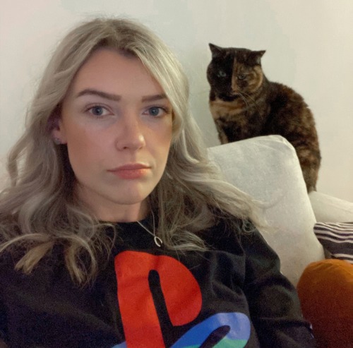 woman with long blonde hair with tortoiseshell cat sitting behind her