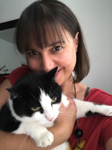 woman with short brown hair holding black-and-white cat