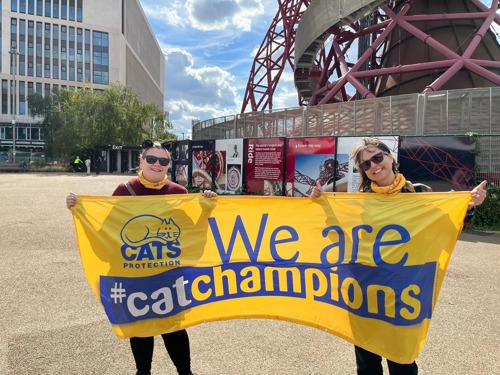 two women holding up yellow banner with Cats Protection logo and 'We are #CatChampions' text