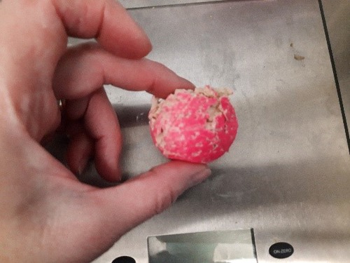 human hand holding chewed pink ball with teeth marks in it