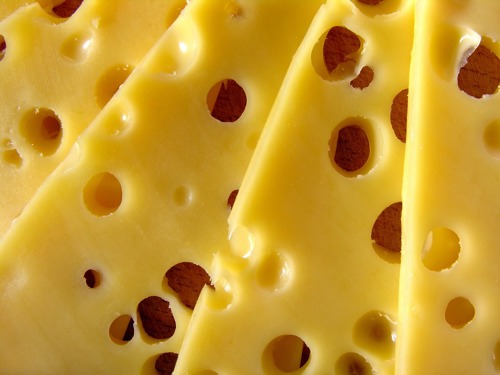 close up image of yellow cheese slices with lots of holes in