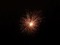 A pink and orange firework exploding in the night sky