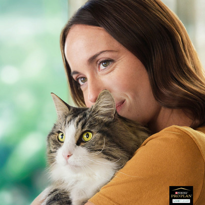 brunette woman holding long-haired grey and white cat