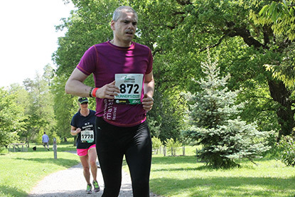man running in a park and wearing a marathon bib number
