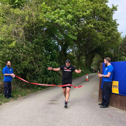 Man running through finish line ribbon at Cats Protection centre