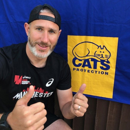 Man giving thumbs up in front of Cats Protection logo