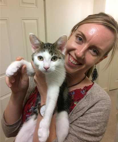 blonde woman holding white and tabby cat