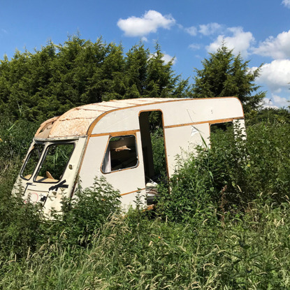 derelict caravan in overgrown field