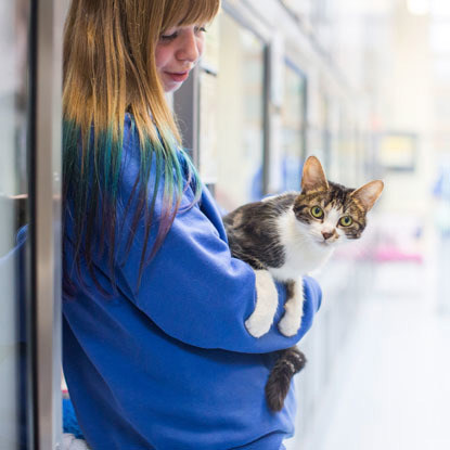 Cats Protection volunteer holding a white and tabby cat