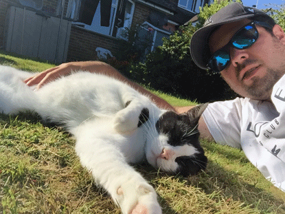 man lying on grass with white and black cat