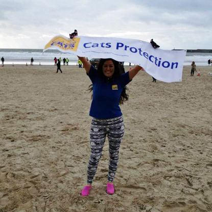 woman holding ip Cats Protection banner on beach