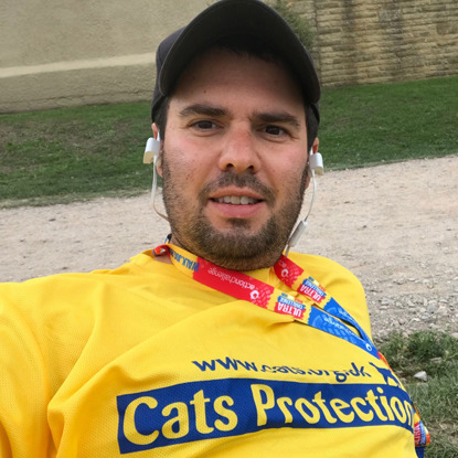 man wearing yellow Cats Protection t-shirt and running race medal