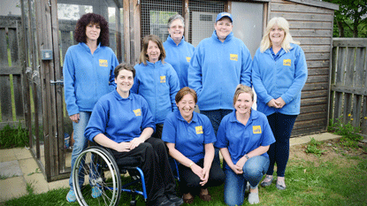 group of Cats Protection volunteers in front of cat pen in a garden