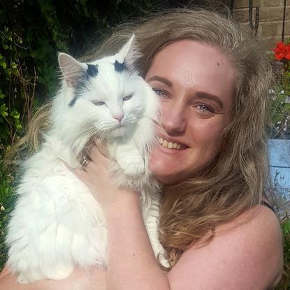 blonde woman holding white cat in garden