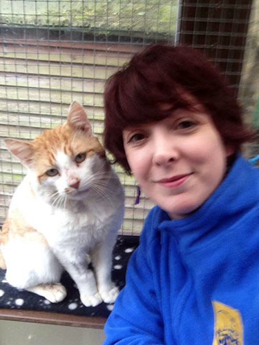 woman with short brown hair with white and ginger cat