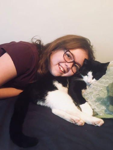 brunette girl cosying up to black and white sleeping cat