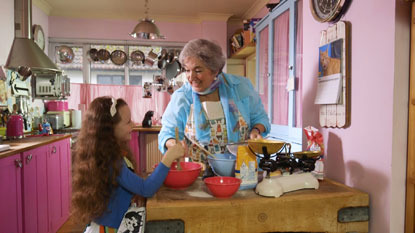little girl in a pink kitchen baking with an elderly lady