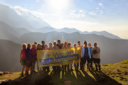 group of people in Himalayas holding banner that says 'We are cat champions'