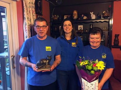man in Cats Protection t-shirt holding cat shaped trophy with two women and a bunch of flowers