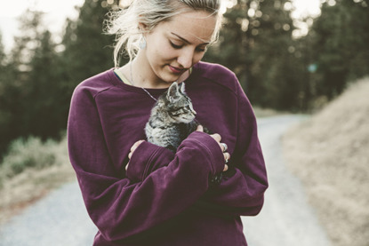 blonde woman holding tabby kitten