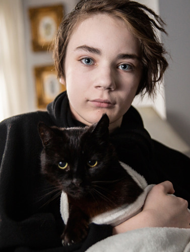 young boy with dark hair holding a black cat