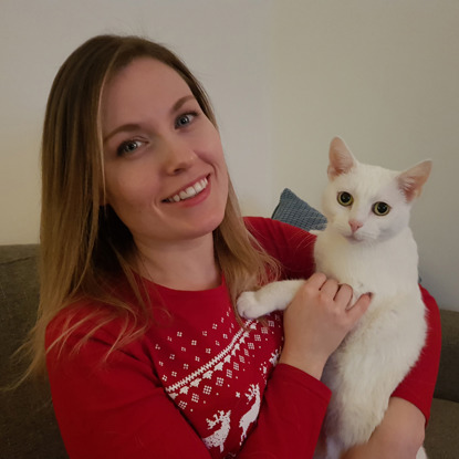 blonde woman in christmas jumper holding white cat