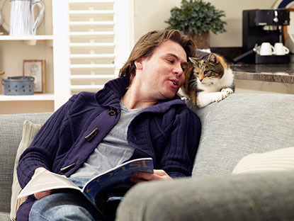 Man sitting on sofa talking to tortie cat