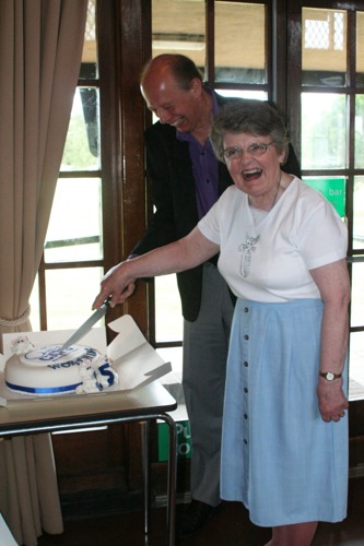Man and woman cutting cake with Cats Protection logo