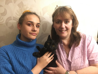 two women holding a black cat