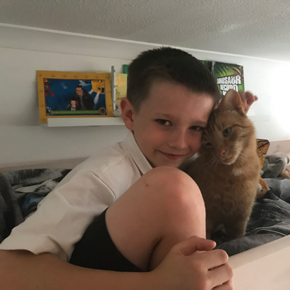 young boy hugging ginger cat
