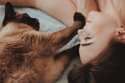 brown cat on bed with woman