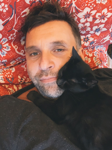 man cuddling black cat