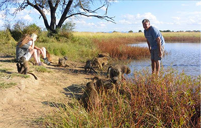 group of people with baboons at the side of a river in Namibia