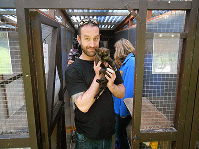 man in black t-shirt holding tortoiseshell cat