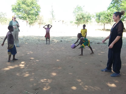 two women playing with a ball with schoolchildren