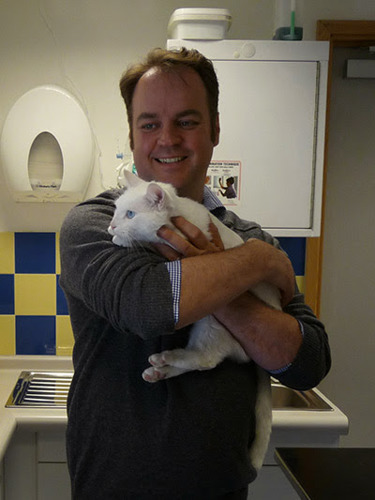 Simon Tofield holding white cat in vet surgery