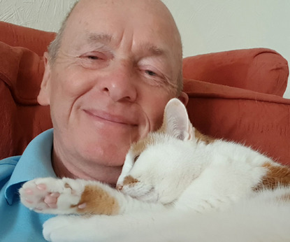 man with ginger and white cat asleep on his chest