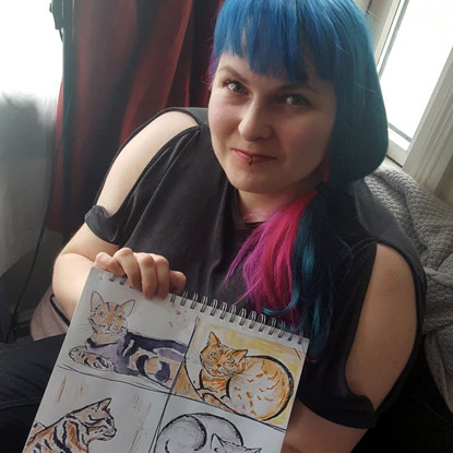 woman with blue and pink hair holding hand-drawn cat portraits