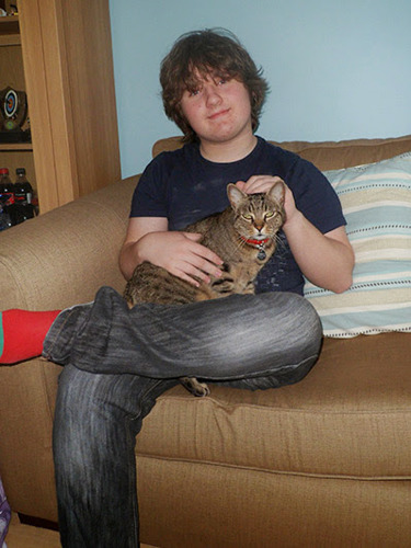 Teenage boy on sofa with tabby cat