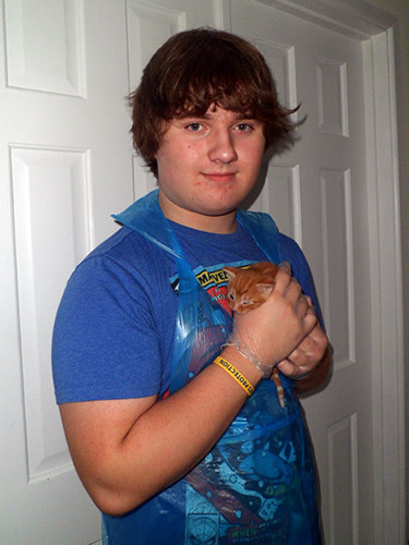 Teenage boy holding a ginger kitten