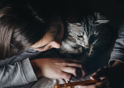 young girl showing tabby cat her iphone