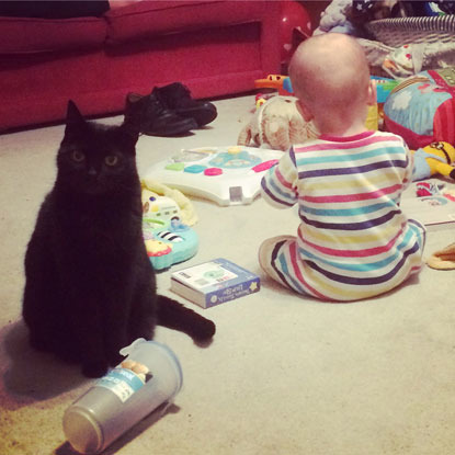 black cat sitting next to baby
