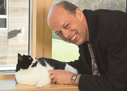 older man in suit with black and white cat on windowsill